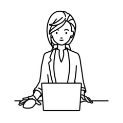 デスクで座ってPCを使っているジャケットの女性