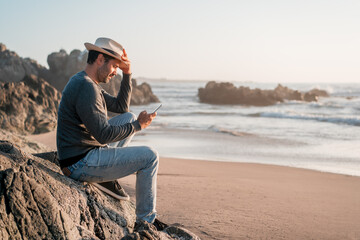 person sitting on the beach with a smartphone happy