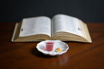 Fototapeta premium Christian Holy Communion sacraments, wine and bread with open Holy Bible at the background.