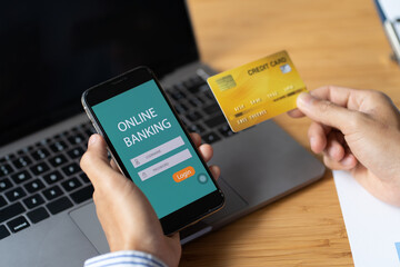 Male hands holding smart phone with online banking screen and credit card in office. online shopping concept.