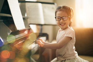 Asian toddler girl look at camera with smiling while playing piano, Happy back to school concept,...