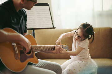 Scene of toddler exploring music instrument, Adorable little girl with music teacher playing guitar...