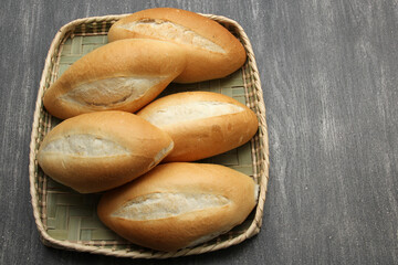 Fresh, delicious, fluffy, hot, freshly made Mexican bolillo bread, white bread, loaf, French bread made from wheat flour ready to eat in a basket on gray wooden table
