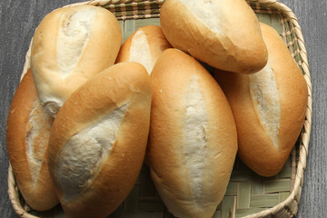 Fresh, delicious, fluffy, hot, freshly made Mexican bolillo bread, white bread, loaf, French bread made from wheat flour ready to eat in a basket on gray wooden table
