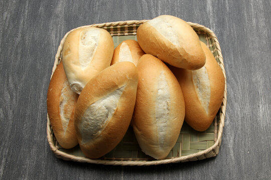 Fresh, delicious, fluffy, hot, freshly made Mexican bolillo bread, white bread, loaf, French bread made from wheat flour ready to eat in a basket on gray wooden table
