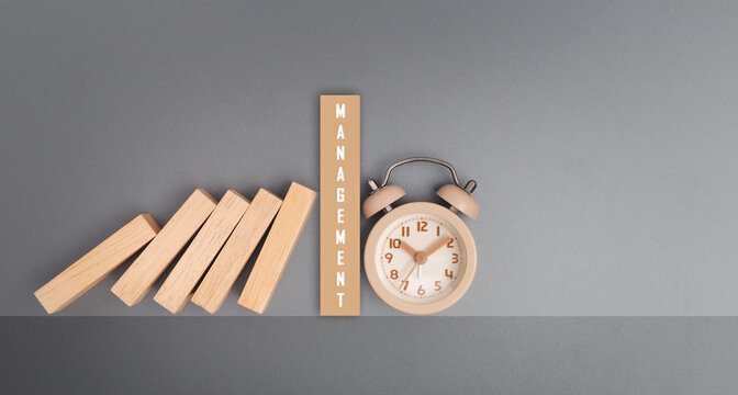 Text MANAGEMENT on wooden block task management clock over gray background.
