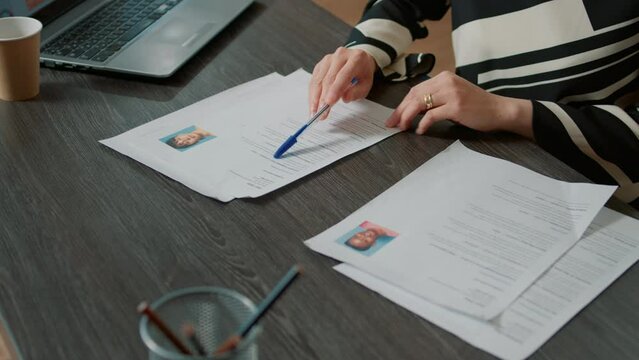 Office worker analyzing candidates cv and application form before attending job interview and hiring people. Recruiter searching on papers for person with business expertise. Close up.