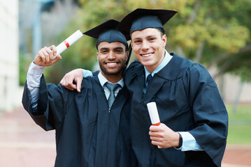 Were on our way to success. Two young college graduates holding their diplomas while wearing cap and gown.