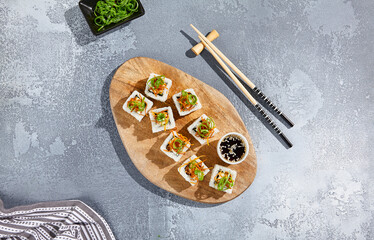 Maki roll with fried carrot and green onion top on wooden board in contemporary composition. Sushi roll with chopsticks on concrete table. Maki sushi in minimal style.