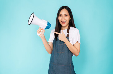 Smile Asian woman holding megaphone with fists clenched celebrating victory expressing success on blue background.