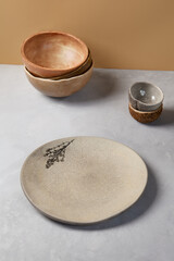 Ceramic dishware in modern style on gray stone background. Empty Handmade crockery in minimalistic composition. Pottery plate on concrete background.