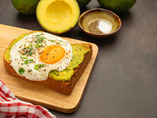 Toast with avocado and eggs served on a wooden cutting board