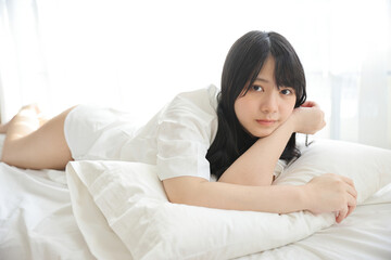 Beautiful young woman waking up in the morning at white bedroom