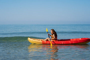 Fototapeta premium woman in life jacket paddling a kayak boat in sea