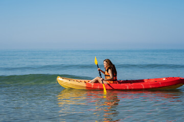 woman in life jacket paddling a kayak boat in sea