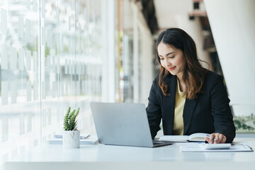 Happy young indian business woman entrepreneur using computer looking at screen working in internet sit at office desk, smiling hindu female professional employee typing email on laptop at workplace