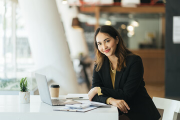 Young asian woman using computer laptop. looking at the camera with showing success. - Powered by Adobe