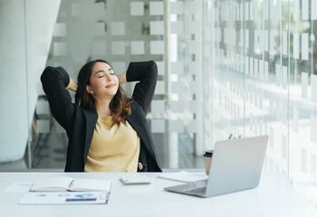 Carefree indian employee resting after busy fruitful workday leaned on office chair puts hands...