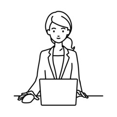 デスクで座ってPCを使っているスーツの女性