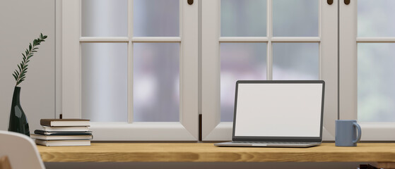 Workspace with laptop on wooden tabletop over the window.