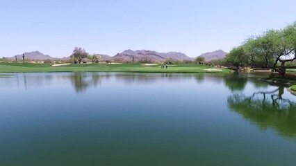 Several golfers walk up to green across from water hazard at Greyhawk Golf Course, Scottsdale, Arizona.