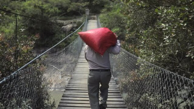 Old man carrying a bag full of coffee in a bridge in latin america