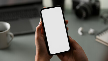 Female officer holding blank screen mobile phone over her workspace table.