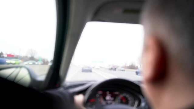 Male Caucasian Person driving on highway freeway in car with blurred background and foreground - close up of person driving car out-of-focus blur bokeh - view from backseat