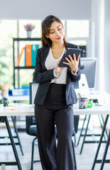 Asian young female professional successful businesswoman secretary employee staff in formal suit pants standing smiling holding touchscreen tablet computer checking email in company office workplace