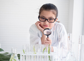 Child girl scientist holding magnifying glass. Girl learning science and doing analysis in the laboratory. Research and development