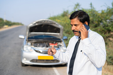 worried Businessman talking on mobile phone with car mechanic while car breakdown at highway road -...