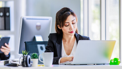 Asian young female professional businesswoman secretary employee in formal suit sitting at working...