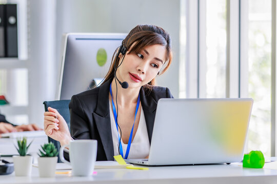 Closeup shot Asian young beautiful female businesswoman operator wearing headset with microphone working at helpdesk service with laptop computer remotely helping consulting with customers in office