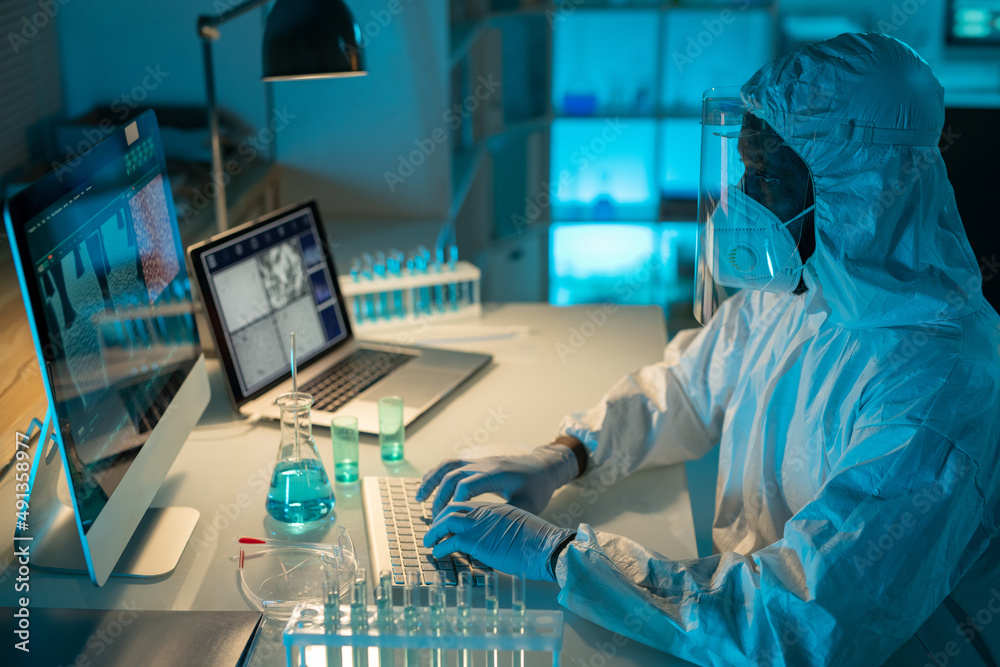 Aufkleber Contemporary African American scientist typing on computer keypad while analyzing results of scientific experiment in laboratory
