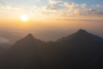 Aerial top view of forest trees and green mountain hills with fog, mist and clouds. Nature landscape background, Thailand.