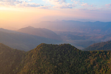 Fototapeta premium Aerial top view of forest trees and green mountain hills with fog, mist and clouds. Nature landscape background, Thailand.