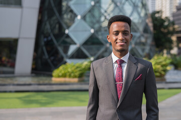 Portrait of handsome young African businessman outdoors in city