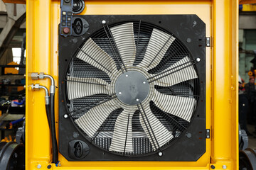 Close-up of part of huge industrial or construction machine with electric fan necessary dor cooling...