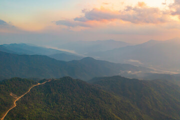 Aerial top view of forest trees and green mountain hills with fog, mist and clouds. Nature landscape background, Thailand.