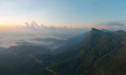 Aerial top view of forest trees and green mountain hills with fog, mist and clouds. Nature...