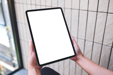 Mockup image of a woman holding digital tablet with blank white desktop screen in cafe