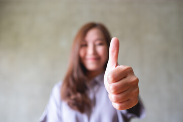 A young asian woman making and showing thumbs up hand sign