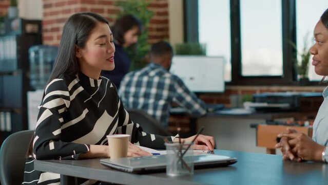 Asian employee greeting african american woman at job interview, talking about application. People meeting to discuss about employment offer and career opportunity, HR recruitment.