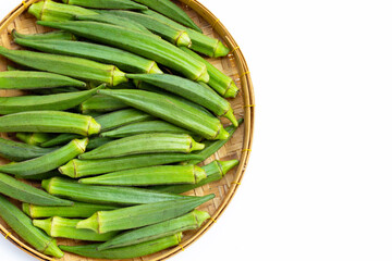 Fresh okra in bamboo weave plate on white background.