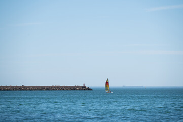Sail boat sails near the pier
