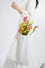 Model with white dress holding a basket of blossom flower in white background for plants and flower advertising , front view