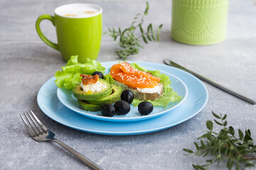 Healthy breakfast. Sandwich with smoked salmon, avocado cheese on lettuce salad leaves and coffee