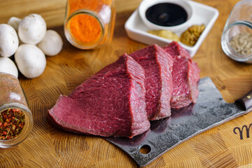 Raw ready for grill beef steaks on knife, mashrooms spices on cutting board. Healthy food concept