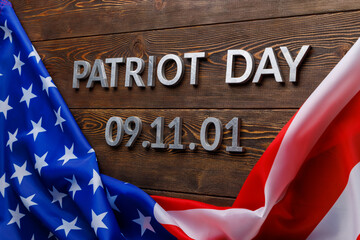 the words patriot day laid with silver metal letters on wooden board surface with crumpled usa flag