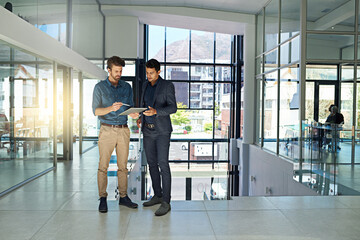 They collaborate on all the big projects. Shot of two colleagues talking together over a digital...